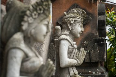 Stone statue with hands in a praying atthe temple' entrance on Bali, Indonesia. Spiritual cullture symbols concept