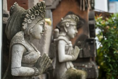 Stone statue with hands in a praying atthe temple' entrance on Bali, Indonesia. Spiritual cullture symbols concept