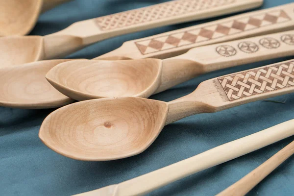 乌克兰人手工雕刻的木制勺子 用烧焦的装饰品放在蓝色布上 木匠工艺概念 — 图库照片