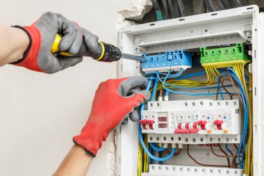 Elektrikçilerin ellerini eldiven takarken ve ana elektrik bağlantı kutusu yerleştirirken kapatın. Elektrik hizmetleri kavramı  