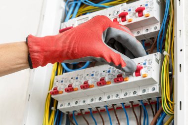 Elektrikçilerin ellerini eldiven takarken ve ana elektrik bağlantı kutusu yerleştirirken kapatın. Elektrik hizmetleri kavramı  