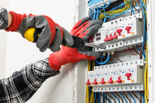将电工的手紧握在工作手套上 安装并保持在电器接线盒内 电气服务概念 图库图片