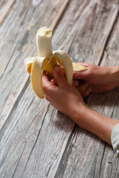 Close up of hands holding open banana. Healthy lifestyle and nutrition concept
