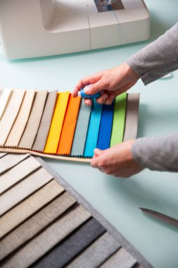 Terzi dikiş işlemi sırasında kumaş örneklerini kullanarak mavi ipliğin doğru rengini seçiyor. İşçilik konsepti 