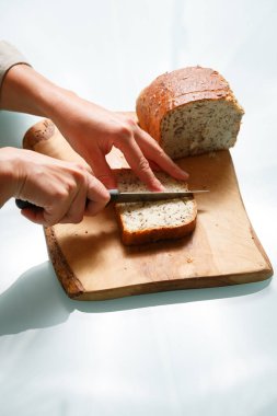 Kadın ellerini kapatıp tahtadan bir parça İskandinav ekmeği kesiyor.