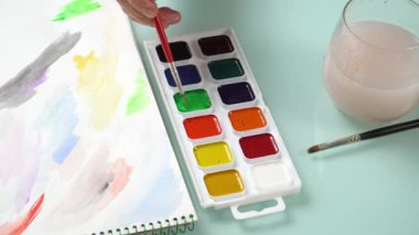 Suluboya paletinden renk alan bir elin görüntüsü. Sanat ve ilham videosu
