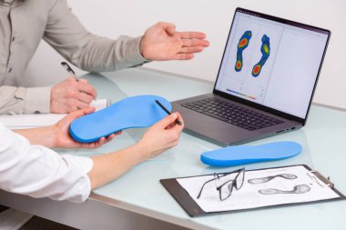 Özel dikey tabanlı bir klinikte, dizüstü bilgisayardaki özel yapım montaj fotoğrafı için erkek hastaya danışmanlık yapan bir doktor. Ayak dinlendirme ilacı konsepti