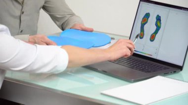 Özel yapım bir klinikte, dizüstü bilgisayardaki test fotoğrafını kullanarak özel yapım özel dikey tabanlı erkek hastaya danışıyorum. Ayak dinlendirme ilacı konsepti