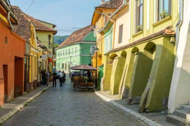 SIGHISOARA, ROMANIA - 8 Ağustos 2019: UNESCO tarafından dünya mirası olarak listelenen Romanya 'nın Sighisoara kentinde sokak kafeleri bulunan Octavian Goga caddesi