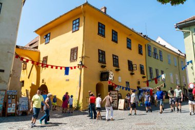 SIGHISOARA, ROMANIA - 10 Ağustos 2019: UNESCO tarafından dünya mirası olarak listelenen Romanya 'nın Sighisoara kentindeki Vlad Drakula' nın doğum yeri olan ortaçağ evinin önünden geçen insanlar
