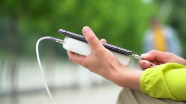 Beyaz enerji bankasıyla şarj ederken cep telefonu kullanan kadın eller. Yavaş çekim. Enerji tasarrufu teknolojisi