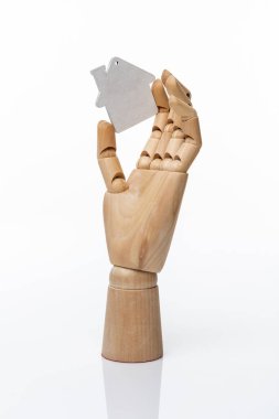 Beyaz ahşap oyuncak ev, emlak sembolü, beyaz arka planda tahta bir mankenin ahşap elinde. Emlak konsepti vuruldu 