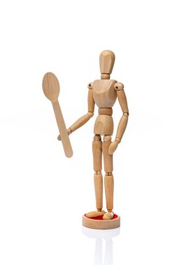 Tahta oyuncak manken beyaz arka planda tek kullanımlık ahşap fspoon tutuyor. Sağlıklı yeme kavramı 