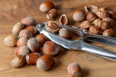 Ahşap zemin üzerinde fındık kıracağı olan çiğ fındık. Beslenme ve kardiyovasküler sistem kavramı