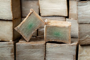 Kahverengi ahşap arka planda iki dilim eski ve kuru geleneksel aleppo organik defne sabunu. Cilt tedavisi kavramı