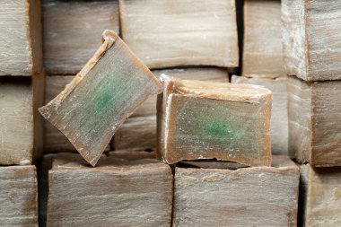 Kahverengi ahşap arka planda iki dilim eski ve kuru geleneksel aleppo organik defne sabunu. Cilt tedavisi kavramı