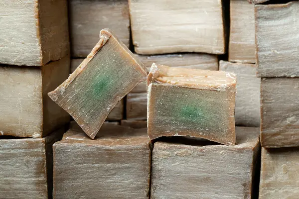 Kahverengi ahşap arka planda iki dilim eski ve kuru geleneksel aleppo organik defne sabunu. Cilt tedavisi kavramı