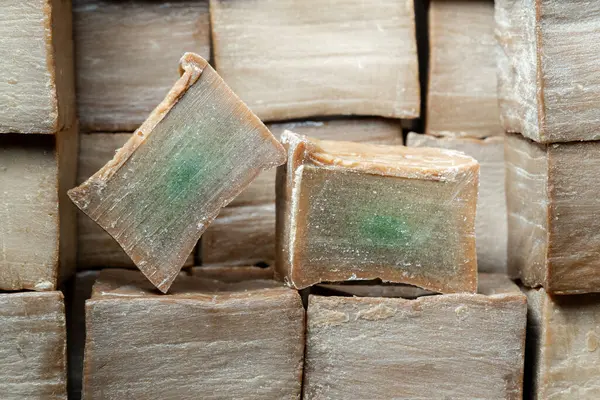 Kahverengi ahşap arka planda iki dilim eski ve kuru geleneksel aleppo organik defne sabunu. Cilt tedavisi kavramı