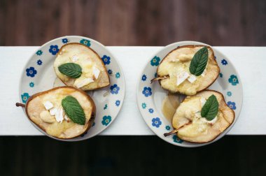 Fırında armut tatlısı, tabakta peynir ve nane yaprağı, bal ve fındık.