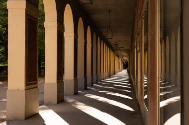Münih 'teki Sunlit Hofgarten atari salonunda tekrar eden kemerler ve kolonlar güçlü gölgeler oluşturuyor. Mimari, seyahat ve kültürel miras projeleri için harika.