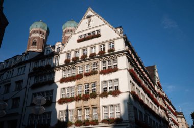 Münih 'teki tarihi bina, karakteristik Bavyera mimarisi, açık renkli koyu kırmızı çatılı. Düzenli pencere düzenleme ve dekoratif ön cephe öğelerine sahip çok katlı bina.