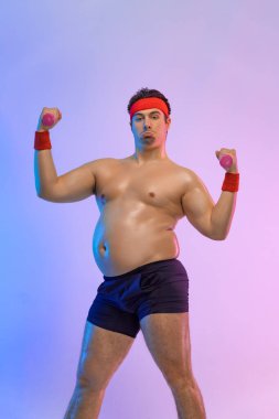 Hamburger ve halterli şişman adam. Pembe arka planda izole edilmiş hamburger yiyen sporcular değil.