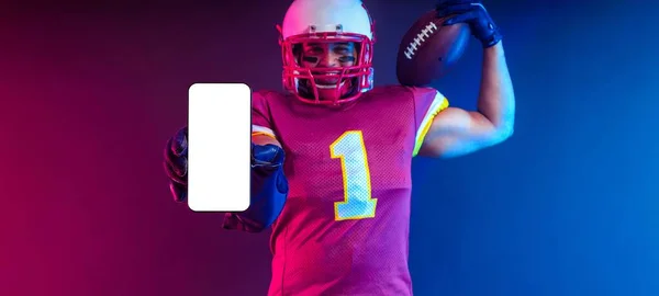 美国足球运动员的横幅上挂着霓虹灯 手里拿着装有白色空白屏幕的大型智能手机 带有复制空间的投注商广告模板 投注广告的模型 — 图库照片