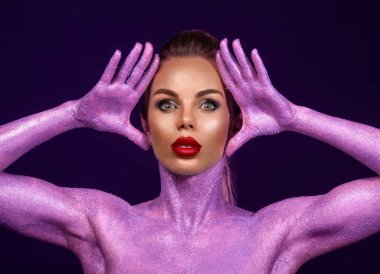 Gözlüklü ve kulaklıklı neon ışıklı kız DJ. Yüzünde ve vücudunda menekşe rengi boyalı güzel bir kadın. Kulüp partisinde seksi TDJ portresi