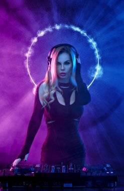 Gözlüklü ve kulaklıklı neon ışıklı kız DJ. Yüzünde ve vücudunda menekşe rengi boyalı güzel bir kadın. Kulüp partisinde seksi TDJ portresi