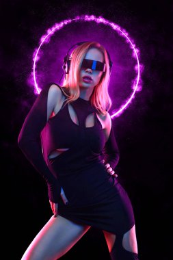 Gözlüklü ve kulaklıklı neon ışıklı kız DJ. Yüzünde ve vücudunda menekşe rengi boyalı güzel bir kadın. Kulüp partisinde seksi TDJ portresi