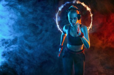 Koşucu kaçıyor. Hızlı koşu. Siyah arka planda koşan güçlü atletik kadın spor giyim kuşamında neon ışıklar takıyor. Spor ve spor motivasyonu