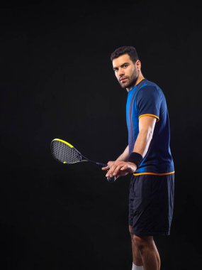 Squash oyuncusu raketle squash sahasında. Sahada raketli, neon renkli bir erkek sporcu. Spor konsepti. Bir spor uygulaması ya da bahis sitesi tasarımı için yüksek kaliteli bir fotoğraf indir