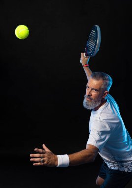 Raketli Padel tenisçi. Sahada raketli, neon renkli bir erkek sporcu. Spor konsepti. Bir spor uygulaması ya da bahis sitesi tasarımı için yüksek kaliteli bir fotoğraf indir