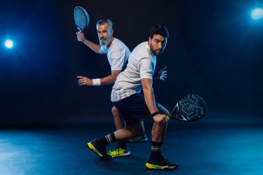 Raketli Padel tenisçi. Sahada raketli, neon renkli bir erkek sporcu. Spor konsepti. Bir spor uygulaması ya da bahis sitesi tasarımı için yüksek kaliteli bir fotoğraf indir