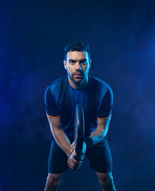 Raketli Padel tenisçi. Sahada raketli, neon renkli bir erkek sporcu. Spor konsepti. Bir spor uygulaması ya da bahis sitesi tasarımı için yüksek kaliteli bir fotoğraf indir