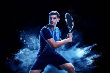 Raketli bir tenisçi. Arka planda tek başına oynayan erkek sporcu