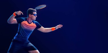 Spor kıyafetli Badminton oyuncusu raket salıncağıyla mekiğe uzanıyor. Stüdyo çekimi.