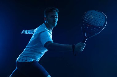 Raketli Padel tenisçi. Sahada raketli, neon renkli bir erkek sporcu. Spor konsepti. Bir spor uygulaması ya da bahis sitesi tasarımı için yüksek kaliteli bir fotoğraf indir