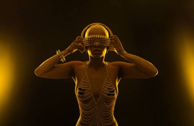 Gözlüklü ve kulaklıklı neon ışıklı kız DJ. Yüzünde ve vücudunda menekşe rengi boya olan güzel bir kadın. Kulüp partisinde seksi TDJ portresi