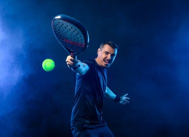 Raketli Padel tenisçi. Sahada raketli, neon renkli bir erkek sporcu. Spor konsepti. Bir spor uygulaması ya da bahis sitesi tasarımı için yüksek kaliteli bir fotoğraf indir