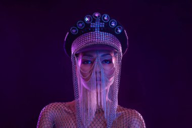 Gözlüklü ve kulaklıklı neon ışıklı kız DJ. Yüzünde ve vücudunda menekşe rengi boyalı güzel bir kadın. Kulüp partisinde seksi TDJ portresi