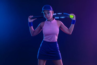 Raketli bir tenisçi. Sahada raketi neon renkli genç bir sporcu kız. Spor konsepti. Bir spor uygulaması ya da bahis sitesi tasarımı için yüksek kaliteli bir fotoğraf indir