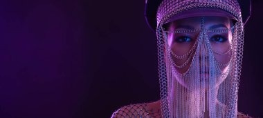 Gözlüklü ve kulaklıklı neon ışıklı kız DJ. Yüzünde ve vücudunda menekşe rengi boyalı güzel bir kadın. Kulüp partisinde seksi TDJ portresi