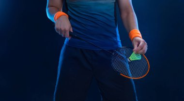 Spor kıyafetli Badminton oyuncusu raket salıncağıyla mekiğe uzanıyor. Stüdyo çekimi.