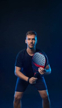Raketli Padel tenisçi. Sahada raketli, neon renkli bir erkek sporcu. Spor konsepti. Bir spor uygulaması ya da bahis sitesi tasarımı için yüksek kaliteli bir fotoğraf indir