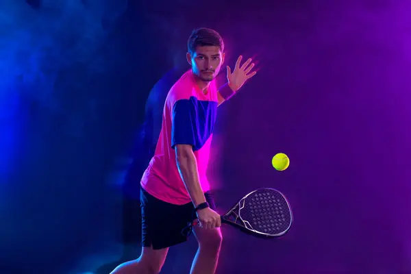 有球拍的帕特尔网球选手 男子运动员球拍在球场上与霓虹灯的颜色 体育概念 下载一张高质量的照片 以设计体育应用或博彩网站 免版税图库照片