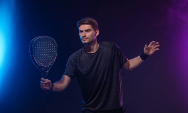 Raketli Padel tenisçi. Sahada raketli, neon renkli bir erkek sporcu. Spor konsepti. Bir spor uygulaması ya da bahis sitesi tasarımı için yüksek kaliteli bir fotoğraf indir