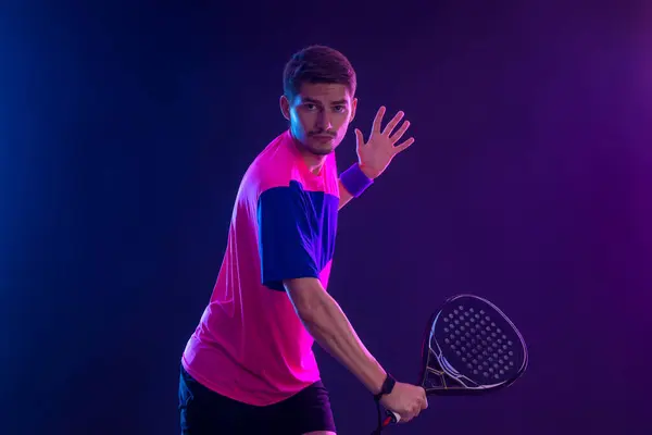 ラケット付きパデルテニス選手 ネオンカラーでコートにラケットを持つ男選手 スポーツの概念 スポーツアプリや賭けサイトのデザインのための高品質の写真をダウンロード ロイヤリティフリーのストック写真
