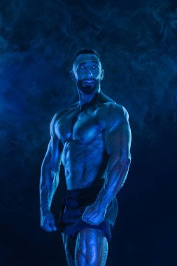 Neon renkli vücut geliştirme sporcusu. Siyah arka planda poz veren formda bir adam. Spor konsepti. Vücut geliştirme yarışması. İndirme, yüksek çözünürlük, fotoğraf
