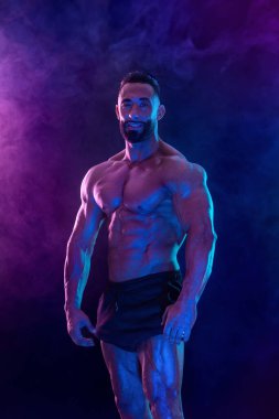 Neon renkli vücut geliştirme sporcusu. Siyah arka planda poz veren formda bir adam. Spor konsepti. Vücut geliştirme yarışması. İndirme, yüksek çözünürlük, fotoğraf